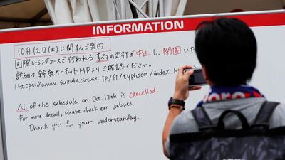 A spectator takes photos of an information board announcing the cancellation of all practice and qualifying sessions for the Japanese Grand Prix scheduled for Saturday due to the approach of Typhoon Hagibis. Reuters