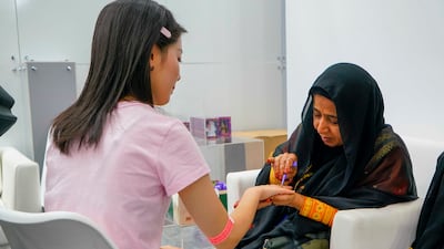 Moza Rashin bin Saifan paints henna on the hands of guests