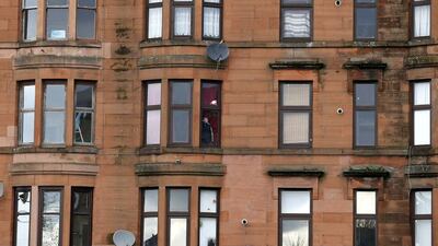 A man looks out a window in Govan, Glasgow. Glasgow now promotes itself instead as a financial and commercial hub - although it still struggles with high unemployment. Stefan Wermuth / Reuters