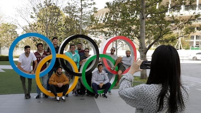A group of students from Uruguay pose for a souvenir picture on the Olympic Rings set outside the Olympic Stadium in Tokyo on Saturday. AP