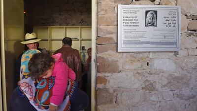 A woman carrying a child walks through a doorway leading to the underground tomb. AFP