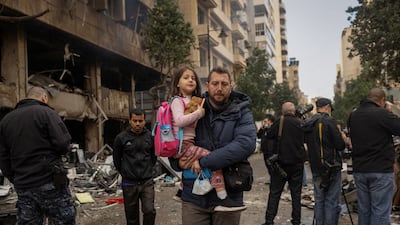 A man carries his daughter to school in the aftermath of an Israeli strike on Mar Elias Street, Beirut. Reuters