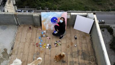 Lebanese Artist Hayat Nazer draws a painting on the roof of her family's apartment building in Tripoli. AFP
