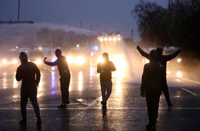 Youths gesture towards a police line blocking a road near the Peace Wall in West Belfast, Northern Ireland. AP