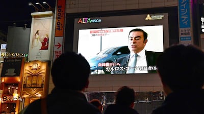 Pedestrians look at a screen showing a news programme featuring Nissan chairman Carlos Ghosn in Tokyo. AFP