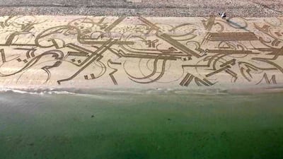 Sand artist Nathaniel Alapide draws murals on the beach using a rake in Jebel Ali. Chris Whiteoak / The National