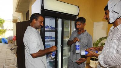 From left, Tariq Ajaib, Mohammed Israr and Chaudary Latif, all from Pakistan and working as gardeners, taking some water and food from a fridge in the garage of the Yel family villa. Jeffrey E Biteng / The National