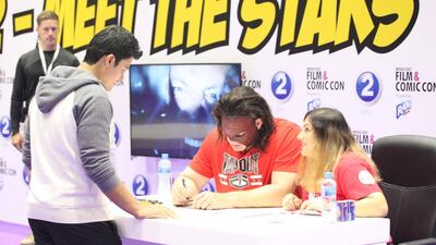 WWE wrestler Kane signs his autograph for a fan at the Middle East Film and Comic Con convention. Courtesy MEFCC