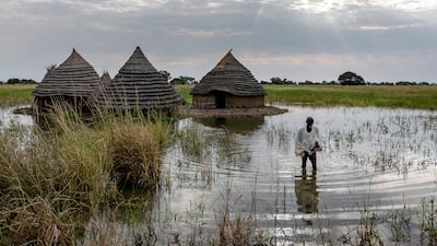 Yel Aguer Deng, who does not know his age, walks through water from his compound to the Wanyhok-Akon road, near Malualkon in Northern Bahr el Ghazal State, South Sudan, Wednesday, Oct. 20, 2021. The worst flooding that parts of South Sudan have seen in 60 years now surrounds his home of mud and grass. His field of sorghum, which fed his family, is under water. Surrounding mud dykes have collapsed. The United Nations says the flooding has affected almost a half-million people across South Sudan since May. (AP Photo / Adrienne Surprenant)