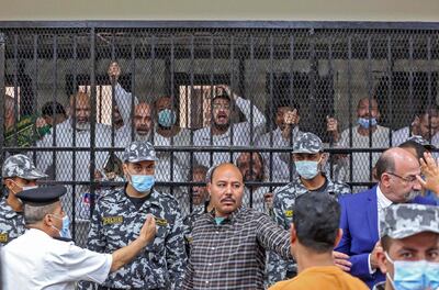 Men charged with illegal excavation and trafficking of antiquities react in the accused dock during the verdict announcement session of their trial in Egypt's capital Cairo on April 21, 2022. - The court handed Egyptian businessman Hassan Ratib a five-year jail sentence, and former MP Alaa Hassanein (standing-L) 10 years, local media reported. (Photo by Khaled KAMEL / AFP)