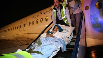 Paramedics carry a wounded Iranian woman from a plane after arriving in Tehran's Mehrabad airport, a day after she was injured in twin suicide bombings near the Iranian embassy in Beirut. Amir Kholousi / AFP