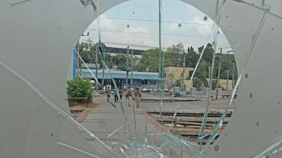 Railway Protection Force personnel walk across tracks as seen from a broken glass window a day after the demonstrations.
