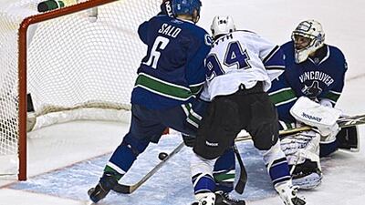 The Canucks goaltender Roberto Luongo, right, can only watch on as the LA Kings tie up the series with an overtime goal.