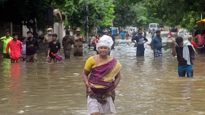 People wade through a flooded street after heavy rain shower in Chennai on November 7, 2021. (Photo by Arun SANKAR / AFP)
