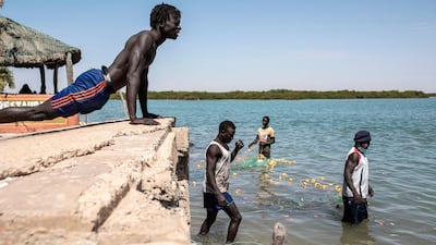 A fisherman does push-ups as his colleagues get their fishing nets ready for their next trip in the protected wetlands area of Joal Fadiouth, in the Thies region of Senegal. AFP