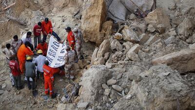 Pakistani rescue workers remove a dead body from the site of landslide in Karachi. Shakil Adil / AP