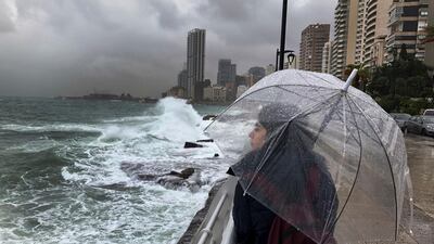 A Lebanese girl shelters for the rain, as she watches waves crash into the seawall in Beirut. AP Photo