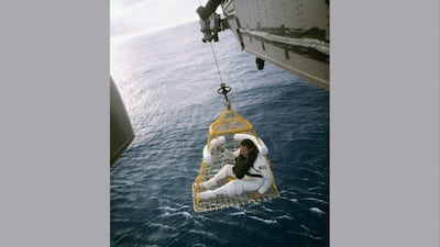Apollo 13 astronaut John L. Swigert Jr sits in a rescue basket as he is lifted aboard a recovery helicopter following splashdown in the Pacific Ocean in 1970