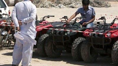 Anas Aman Paracha sits on an ATV with his father Aman Ullah watching, prior to the start of an auction of vehicles owned by Nakheel on the Palm Jumeirah.
