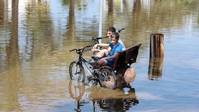 Children play with their bicycles along a waterlogged street in Dubai's Al Furjan district. Pawan Singh / The National