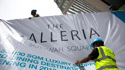 Workers hang a banner for the new Galleria Mall in Sowwah Square on Al Maryah Island. Silvia Razgova / The National