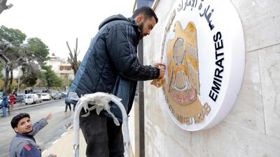 Workers clean the metal plaque on the outside wall of the United Arab Emirates embassy in Damascus, Syria. EPA