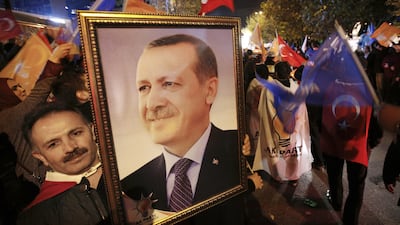 A supporter of the AKP holds a portrait of Turkey's president Recep Tayyip Erdogan outside AKP headquarters in Istanbul as people celebrate the AKP's electoral victory on Sunday, November 1. Emrah Gurel / AP Photo