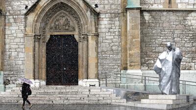 A Sarajevo citizen passes the monument of Pope John Paul II in front of the Catholic Cathedral during snowfall in Sarajevo, Bosnia and Herzegovina. EPA