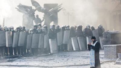 An Orthodox priest prays between police and protestors. Rob Stothard / Getty Images