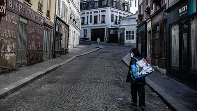 A woman wearing a face mask walks on a deserted street transformed into a movie set, in Paris, France. EPA