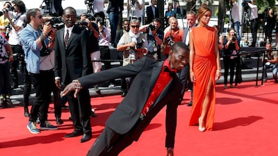 Cast member Souleymane Deme, centre,performs on the red carpet as he arrives with director Mahamat-Saleh Haroun, left, and cast member Anais Monory for the screening of the film "Grigris". Jean-Paul Pelissier / Reuters