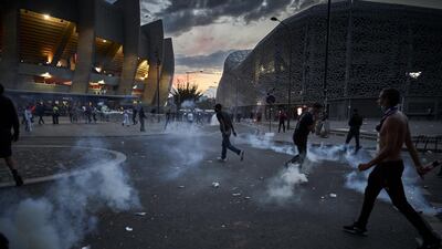 PSG fans run through tear gas during confrontations with police outside Parc de Princes. Getty