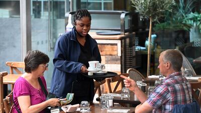 A waitress attends to customers at a restaurant in London. The services sector has struggled to cope with a surge in demand owing to staff shortages. EPA
