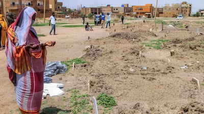 A woman prays by a makeshift grave in Khartoum. AFP
