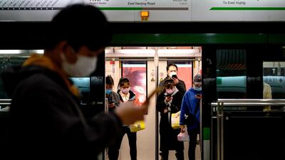 People wearing protective facemasks use their phones on the subway in Shanghai. AFP