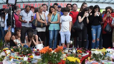 People mourn in front of candles and flowers at the site of a Munich shopping centre where an 18-year-old German-Iranian student killed nine people. Christof Stache / AFP
