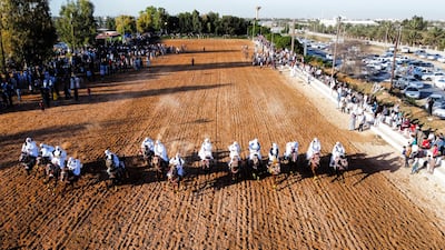Men wearing traditional costumes ride horses during a race in Misrata.