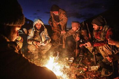 Turkish-backed Syrian fighters warm up around a fire at a position near the northern Syrian town of Manbij on December 28, 2018. AFP
