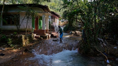 Floodwater flows past homes in Sarasavigama village. AP