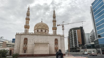 A woman walks along the Sheikh Hamdan Mosque in Deira. Overcast skies will turn to rain on Satuday. Victor Besa / The National