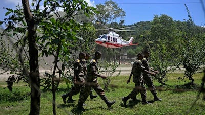 Army personnel walk past a helicopter landing with rescued flood-affected residents from flash floods, at an army camp in Battar Bazar town in Nepal's Nuwakot district . AFP