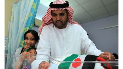 Ali Hamad cradles his grandson, Zayed Hamad Mubarak Sabaan, who was born at 12.37am on National Day.