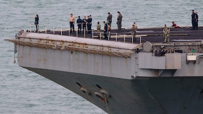 Crew members stand on the flight deck as the aircraft carrier sails towards the Thai port. AFP