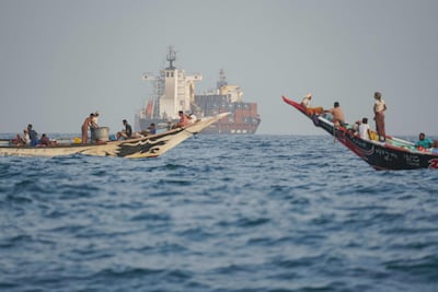 People sail boats past container ships anchoring near the Bab Al Mandeb strait off Yemen's coast in the Gulf of Aden on August 6, 2026. AFP