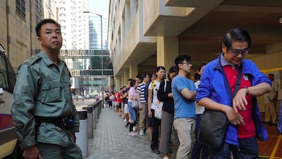 A Hong Kong policeman watches as people line up to vote outside a polling centre. AP Photo