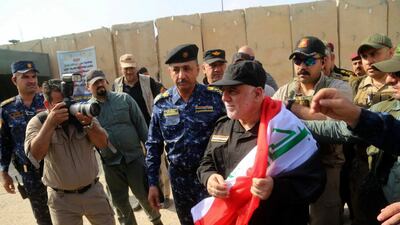 Iraq's Prime Minister Haider al-Abadi, center, holds a national flag upon his arrival to Mosul, Iraq, Sunday, July 9, 2017. Backed by the U.S.-led coalition, Iraq launched the operation to retake Mosul from Islamic State militants in October. (Iraqi Federal Police Press Office via AP)