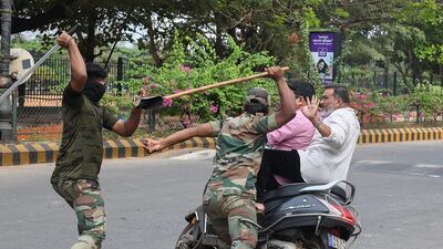 The Karnataka Reserve Police Force confront two men on a scooter who rode too close to a barricade set up on a street in Mangalore. AFP