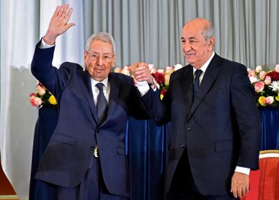 Interim president Abdelkader Bensalah, left, holds the hand of the new Algerian President Abdelmadjid Tebboune. AFP