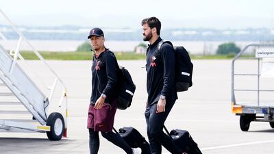 Liverpool's Roberto Firmino and goalkeeper Alisson board the plane at John Lennon Airport. PA