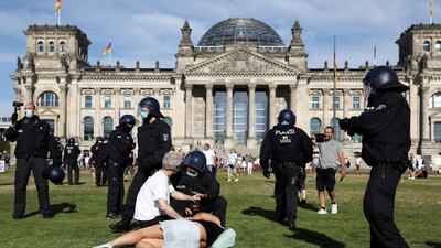 A police officer talks to demonstrators on the ground next to the Reichstag during a protest against the government's restrictions amid the coronavirus disease (COVID-19) outbreak, in Berlin, Germany. REUTERS